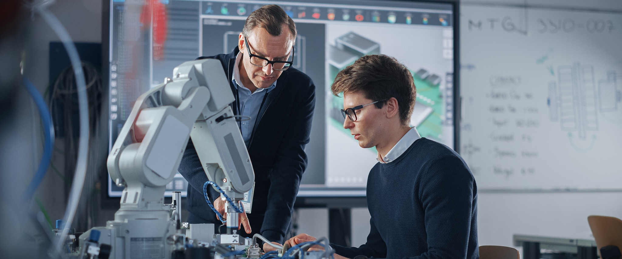 Ausbilder mit Studierendem am Roboter