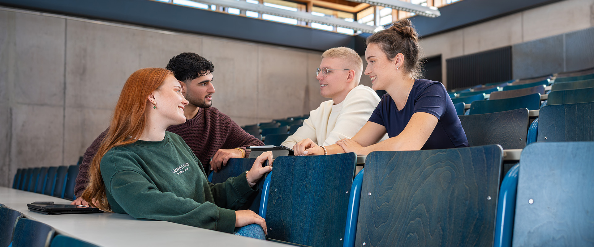 Studentengruppe sitzt im Vorlesungssaal und unterhält sich freundlich miteinander