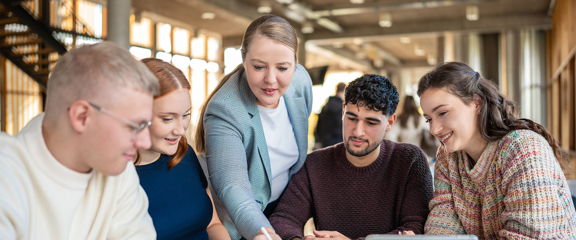 Prof. Dr. Wibke Heidig erklärt Studierenden im Foyer etwas am Tablet