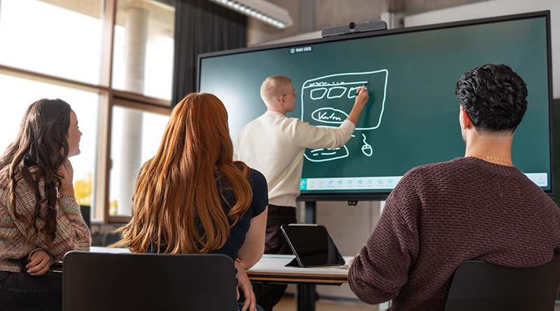 Studierendengruppe sitzt im Projektraum und arbeitet gemeinsam am Touch-TV